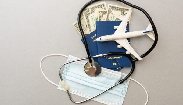 Travel and healthcare concept. Top view of face mask, hand sanitizer, passport, stethoscope and toy plane isolated on blue background with copy space
